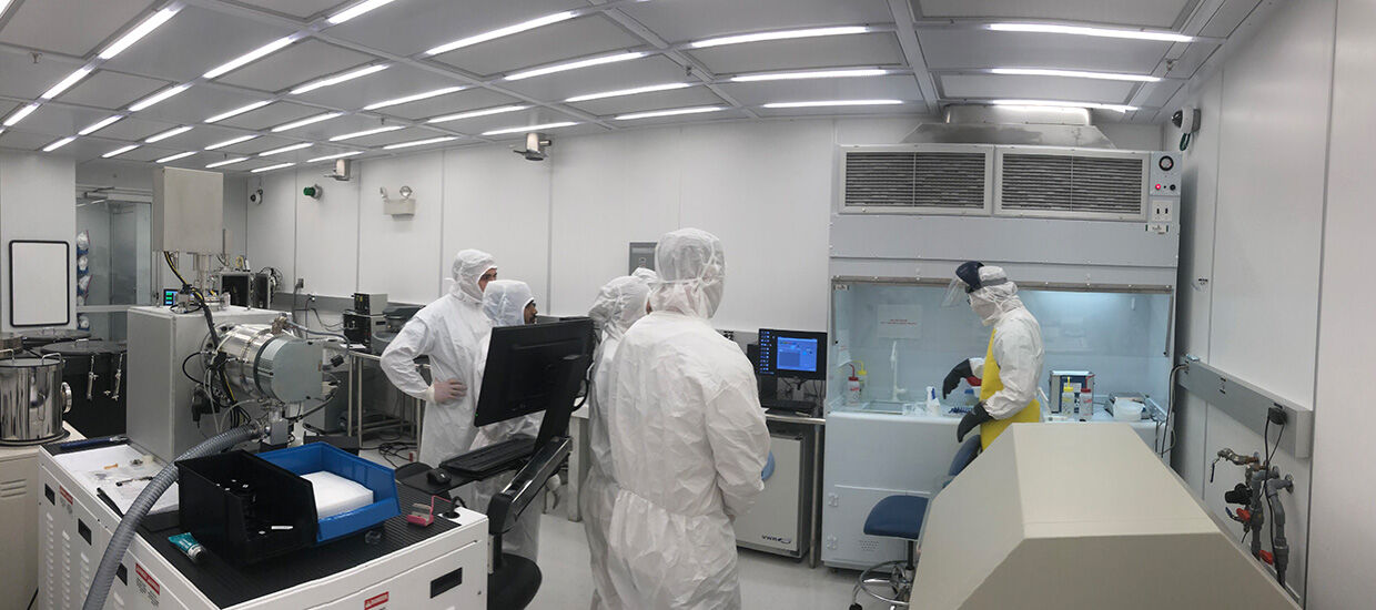 Research staff in protective gowning working inside a biotech pharmaceutical clean room