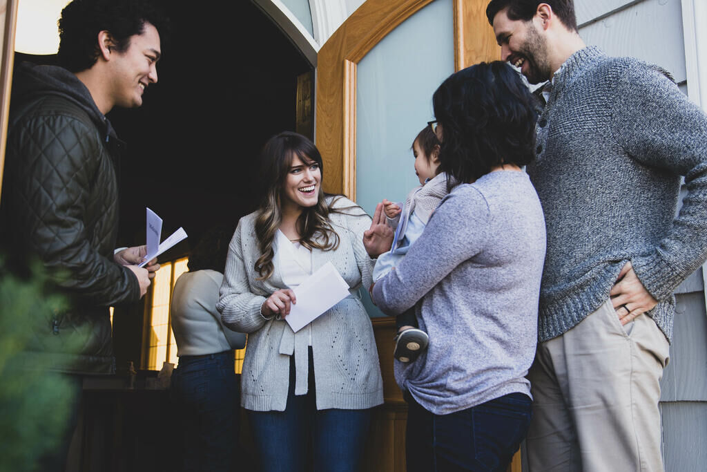 Church greeters welcoming a family at the entrance while staying alert to who comes through the door