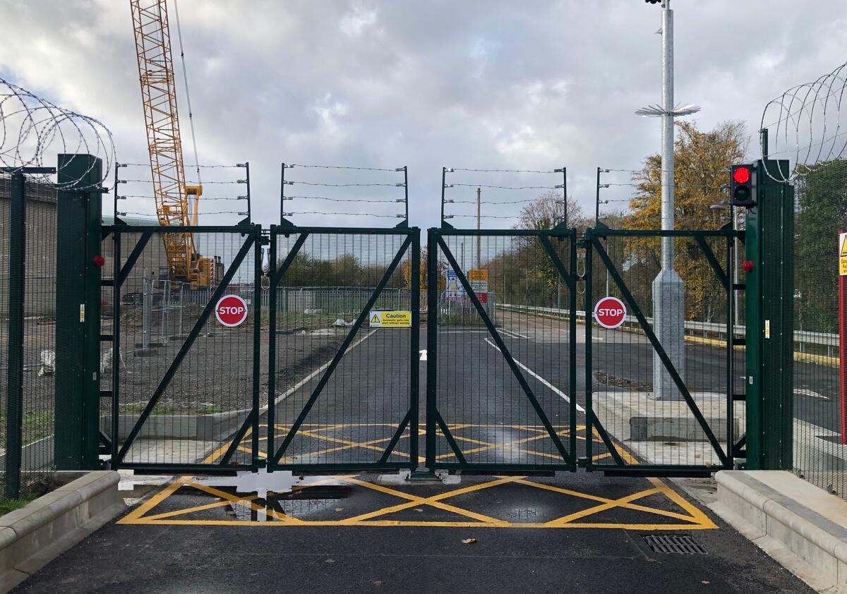 Locked construction site gate with anti-climb mesh and razor wire securing the site perimeter
