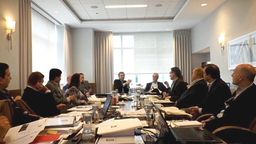 Executives reviewing due-diligence security assessment findings around a boardroom table before a lease, acquisition, or vendor decision